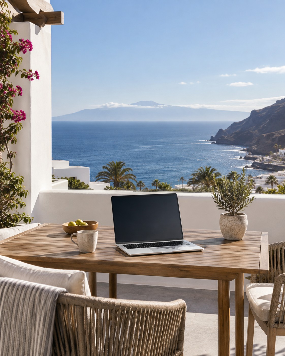 Symbolbild: helle Terrasse einer Ferienwohnung mit Laptop und Meerblick